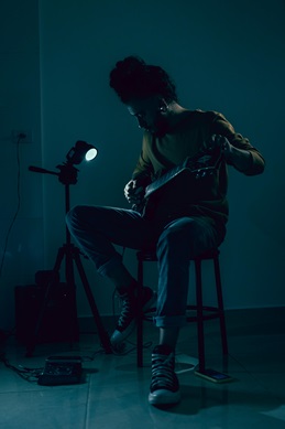 guitarist tuning a guitar while seated